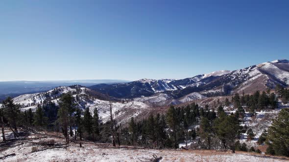 Drone shot panning right to left over a tree line showing a mountain