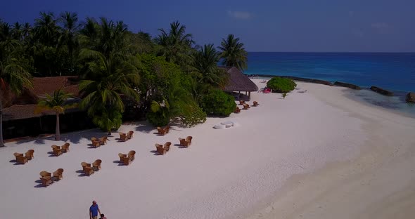 Daytime fly over clean view of a paradise sunny white sand beach and blue sea background in high res