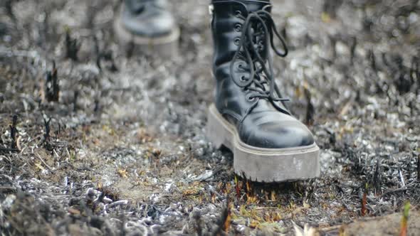 Modern Girl in Fashionable Leather Black Boots with High Soles Walks Along the Burned Ash From the