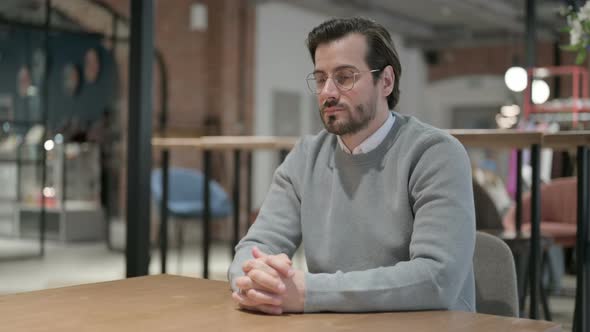 Pensive Young Man Thinking While Sitting in Cafe