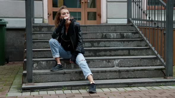 Sad Woman is Sitting on Stone Stair of House and Smoking Vape Pen Thinking About Her Life