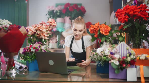 Woman Florist Discusses the Order By Talking on Video Call Using a Laptop and Screen Tablet 