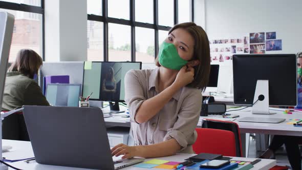 Portrait of asian woman removing face mask at modern office