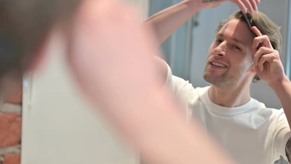 Rear View of Young Man Doing Combing Hair in Mirror