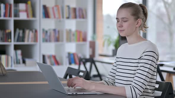 Laptop Use By Young Woman Smiling at Camera in Library 