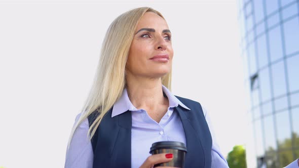 Businesswoman Standing Outside a Modern Corporate Building with Coffee Cup