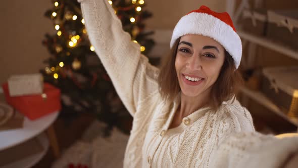 POV First Person View Happy Cheerful Excited Woman in Festive Santa Hat Taking Selfie on Background