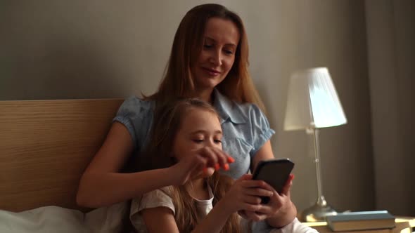 Closeup of Happy Young Mother Hugging to Preschool Daughter Together Browsing and Surfing Internet