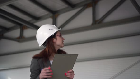 Young Woman in a Helmet Scared Off at a Construction Site. The Boss Woman in a Suit Keeps Records of