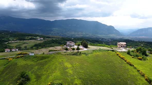 Aerial shot of a vast mountain landscape with house and cloudy sky