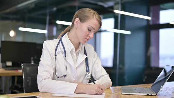 Focused Young Doctor Doing Paperwork in Modern Office 