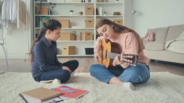 The Teacher Teaches Teenage Girl To Play Guitar While Sitting on the Floor