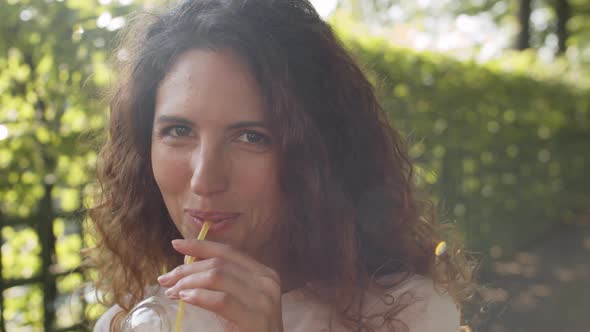 Portrait of Happy Woman Drinking Juice in Park