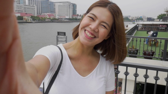 Smile beautiful Asian woman taking selfies on a smartphone.