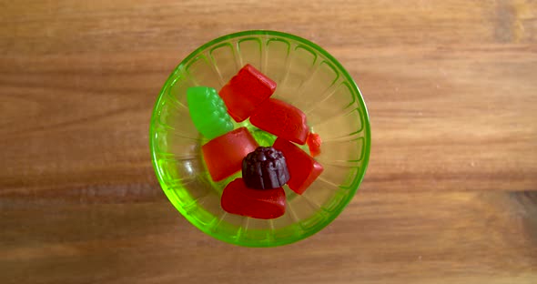 Top down shot of hands taking gummy candies out of a glass dish