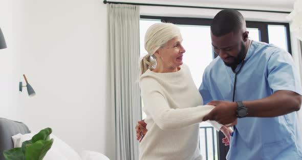 Video of happy african american male doctor taking care of caucasian senior woman