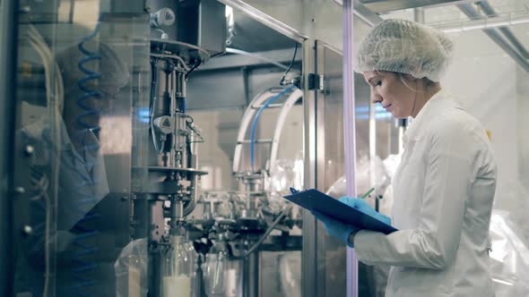 One Worker Checks Machines Filling Bottles with Milk. Quality Control of Production Line at a