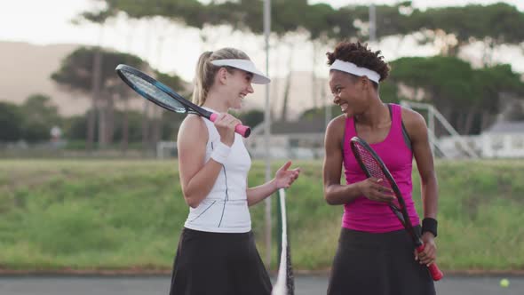 Video of happy diverse female tennis players laughing and talking after match