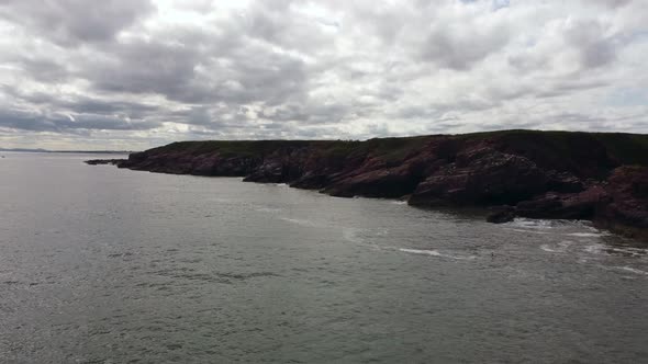 Drone View of the Sea with a Rocky Shore with a Cloudy Sky in the Background