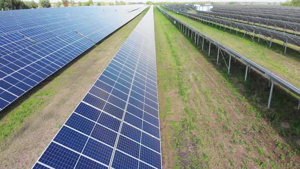 Aerial View of Solar Power Station. Panels Stand in a Row on Green Field. Summer