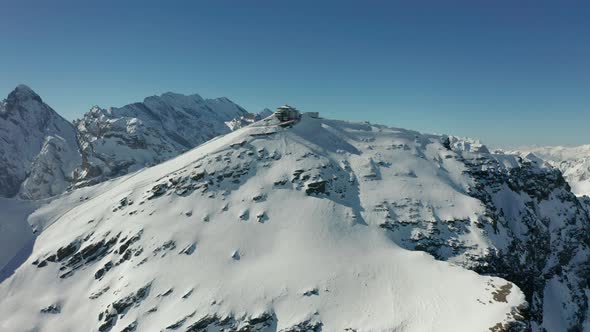 Aerial of building on top of snow covered mountain