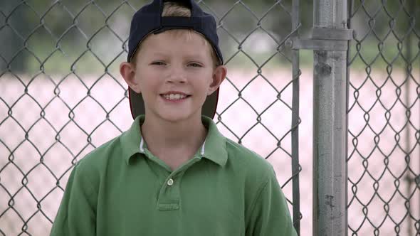 Slow motion of boy hitting baseball mitt as he turns and smiles.