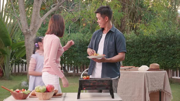 Happy Asian family having a barbecue-BBQ party together in the garden at home.