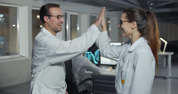 Cheerful Technicians Giving High-five in Electronic Lab