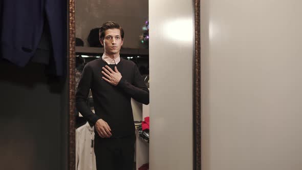 Handsome Man Is Trying on a Black Soft Sweater in a Showroom of Designer Shop