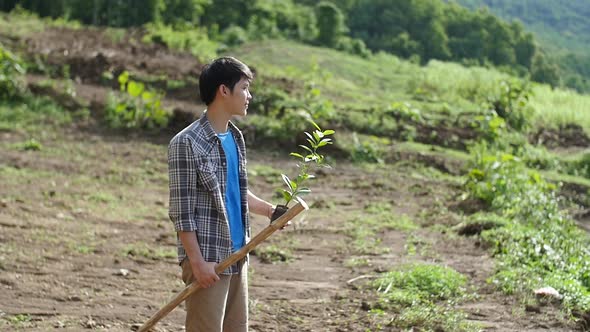 Young Man Holding Plant And Finding Location For Planting Tree