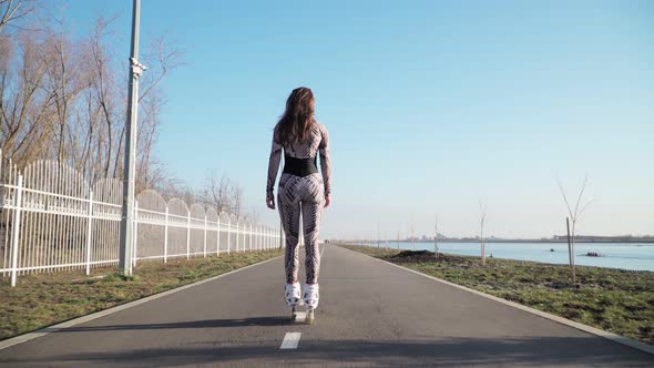 Rides Girl Roller Skating along the path on the background of a beautiful lake