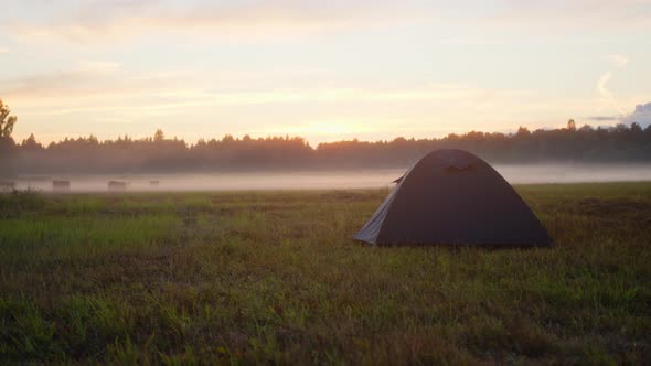 Travelers Sleep in Tent at Dawn with Magnificent Beautiful Sunrise Over Forest with Haze From Fog