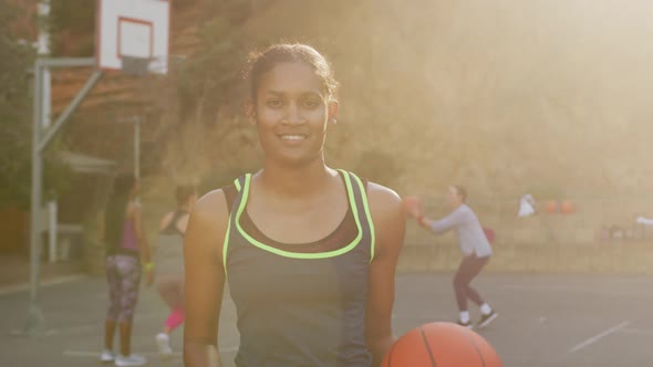 Portrait of african american female basketball player holding ball and looking at camera