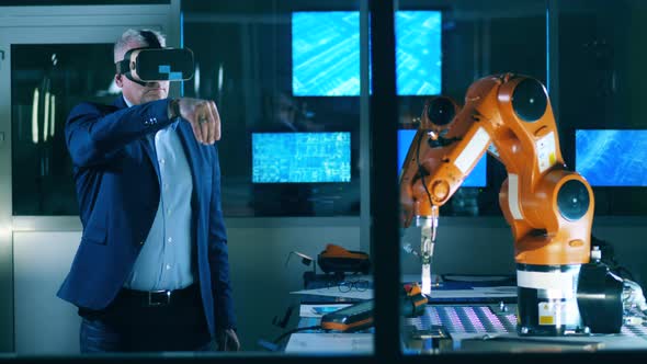 A Man in a Business Suit Is Wearing VRglasses and Managing a Robot