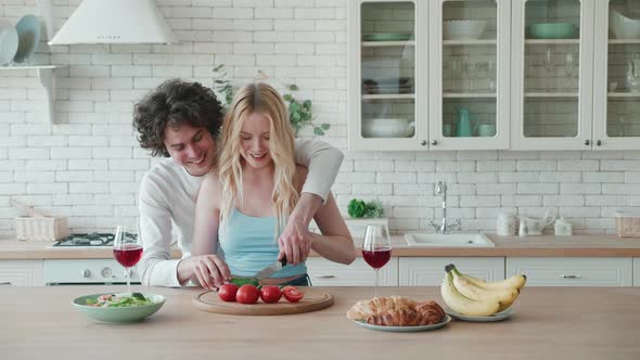 Smiling Young Teens Couple Cutting Fresh Vegetable Salad Talking Having Fun Cooking Together in