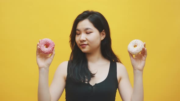 Young Asian Woman Choosing Pink and White Doughnuts in Her Hands. Delicious Dessert
