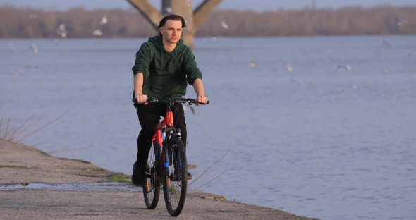 Bicyclist Riding Bike at River Embankment Slow Motion