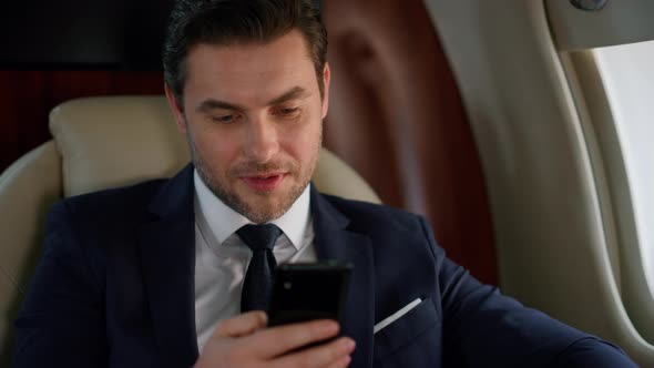 Successful Man Looking Smartphone at Airplane Window