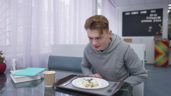 Male Student Smelling Delicious Dessert in Canteen Smiling