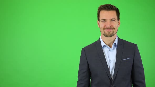 A Young Handsome Businessman Walks Into the Frame and Smiles at the Camera - Green Screen Studio