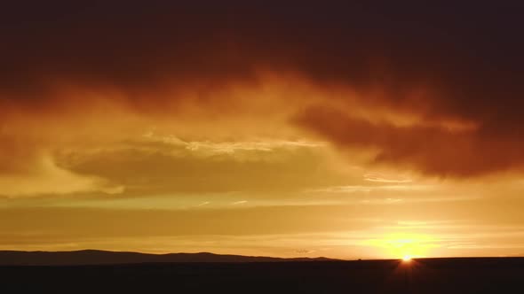 Colorful Wyoming sunset as cars move across the sun on the horizon