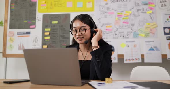 Happy female glasses wears headset video calling on laptop