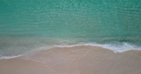 Beautiful birds eye tourism shot of a white paradise beach and blue water background in vibrant 4K