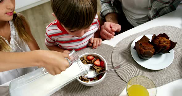 Girl pouring milk to cereal bowl