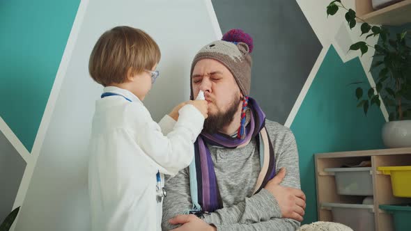 Father and Child Playing Clinic and Doctor Little Boy in Medical Gown with Stethoscope Treats Runny