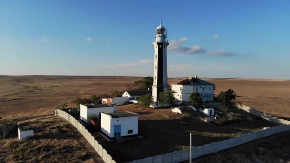 A Typical Striped Lighthouse on the Coast of the Steppe Area in the Evening. Seashore Steep Aerial