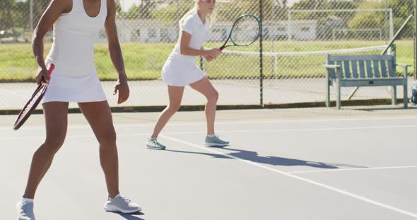 Video of happy diverse female tennis players exercising on court