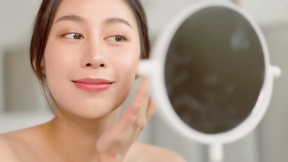 Happy attractive asian woman apply skincare cream on face and body