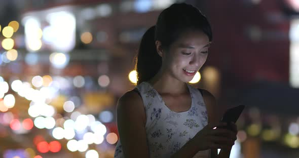 Woman using mobile phone in city at night 