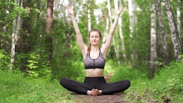 An Attractive Girl Performs a Sports Exercise in the Forest a Sexy Sportswoman